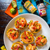Platter of shrimp appetizers with hot sauce bottles on a wooden table
